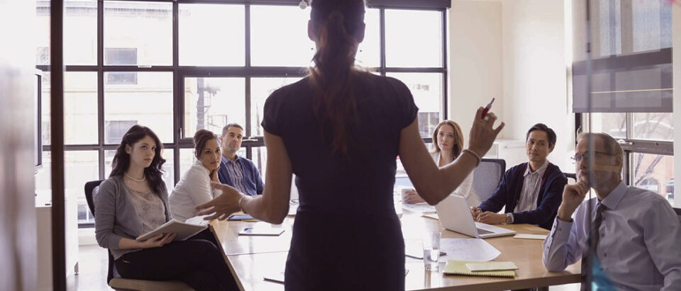 Female leader confidently presenting to team in a boardroom, demonstrating mental fitness and leadership in action.